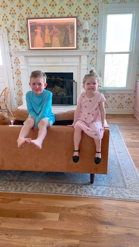 2 smaller kids smiling as they balance on a couch.