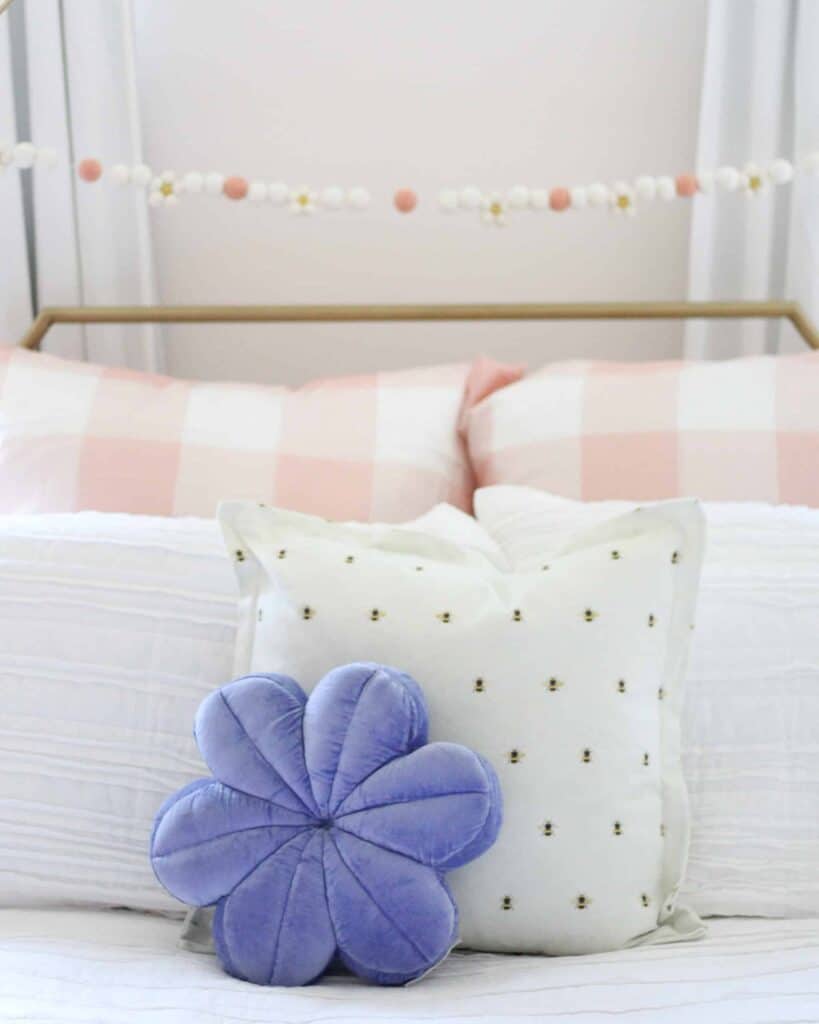Toddler girl bedding with bee pillow and purple flower pillow.