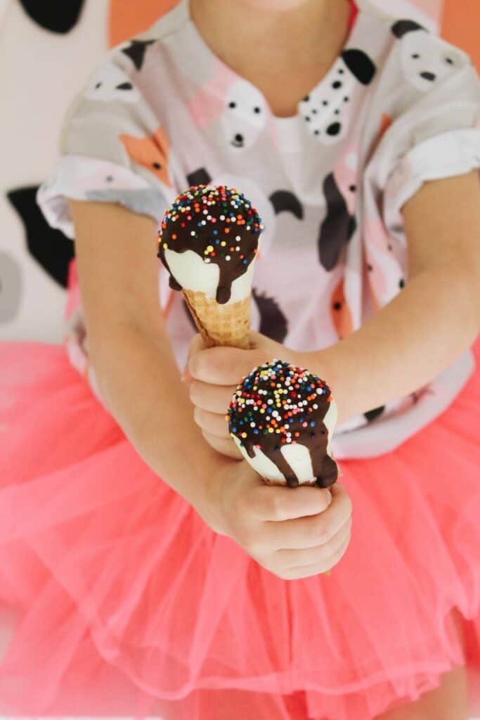 Close up of little girl holding ice cream cone cake pops.