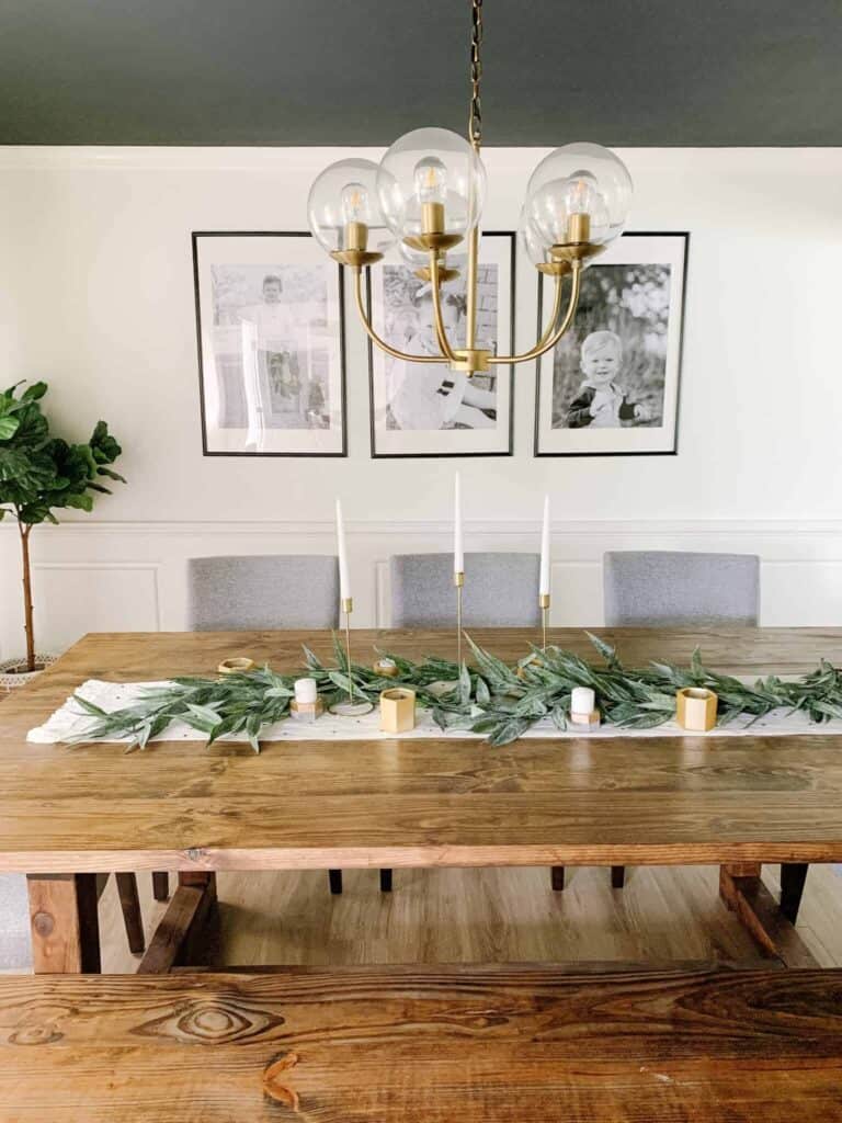 Long rectangular table with candlesticks, runner, greenery, and smaller candles.