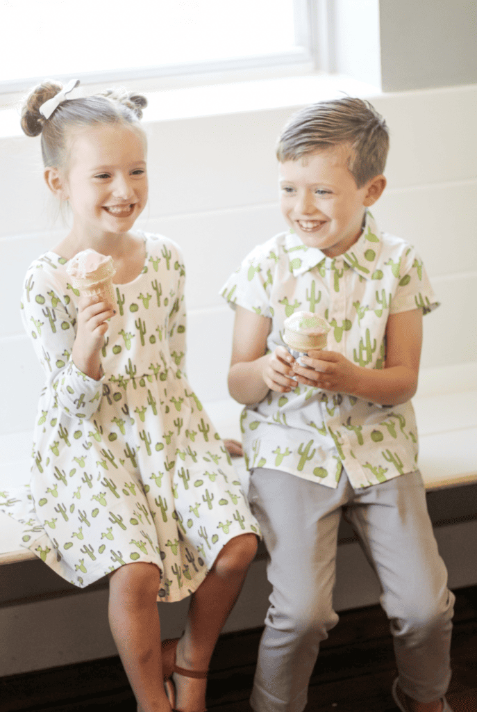 Little girl and little boy laughing and holding vanilla ice cream cones.