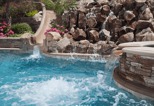 Backyard pool with slide and hot tub.