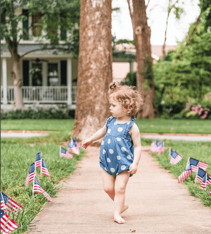 4th of July toddler walking with American flag.