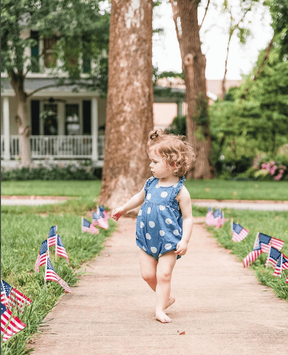 4th of July toddler walking with American flag.