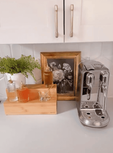 Coffee bar table centerpiece idea with an espresso machine, elevated tray, and decorative plants and frame.