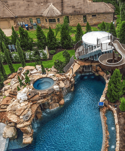 Large swimming pool with 140 ft. slide is the definition of luxury backyard pools with slides.