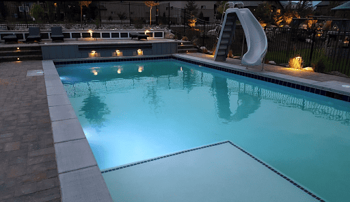 Stand alone luxury backyard  pools with slides at dusk.