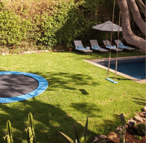 What a serene backyard filled with a trampoline, pool, and swing.