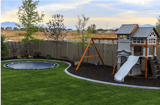 Backyard trampoline ideas include a playhouse with inground trampoline.