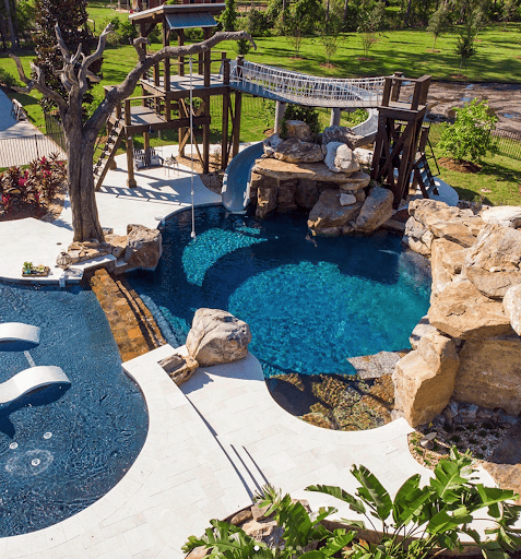 Luxury backyard pools with slides can't get any better in this complete outdoor playground oasis.