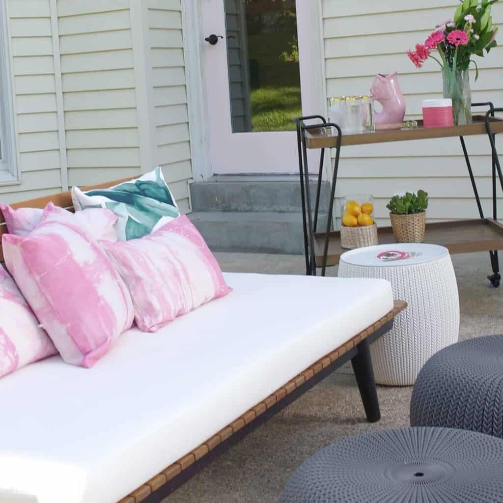 Outdoor table set up with chairs and pouf on a patio