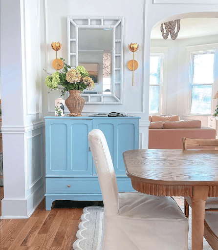 bright blue sideboard, gold sconces, and light wood dining table