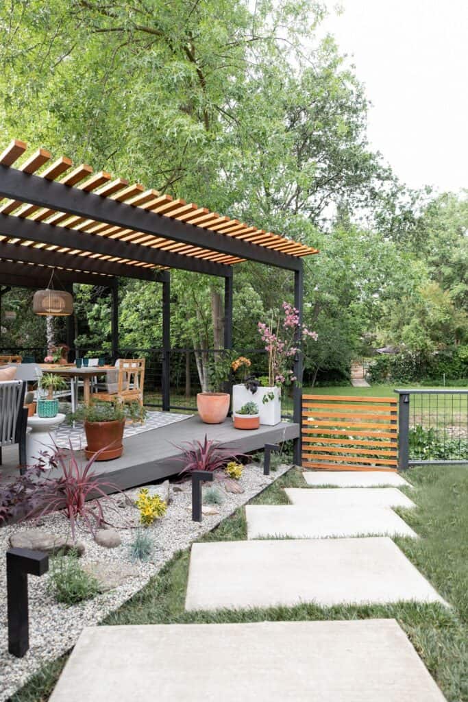 Backyard patio steps of rounded stone lead to an extensive deck with lots of greenery and beautiful details.