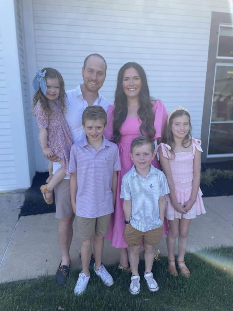 Family in front of home with four kids and parents.