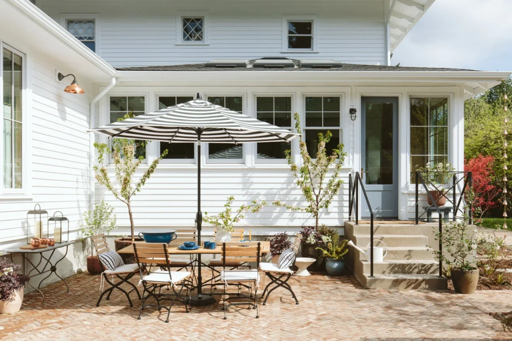 Concrete backyard patio steps lead to a herringbone pattern brick patio.