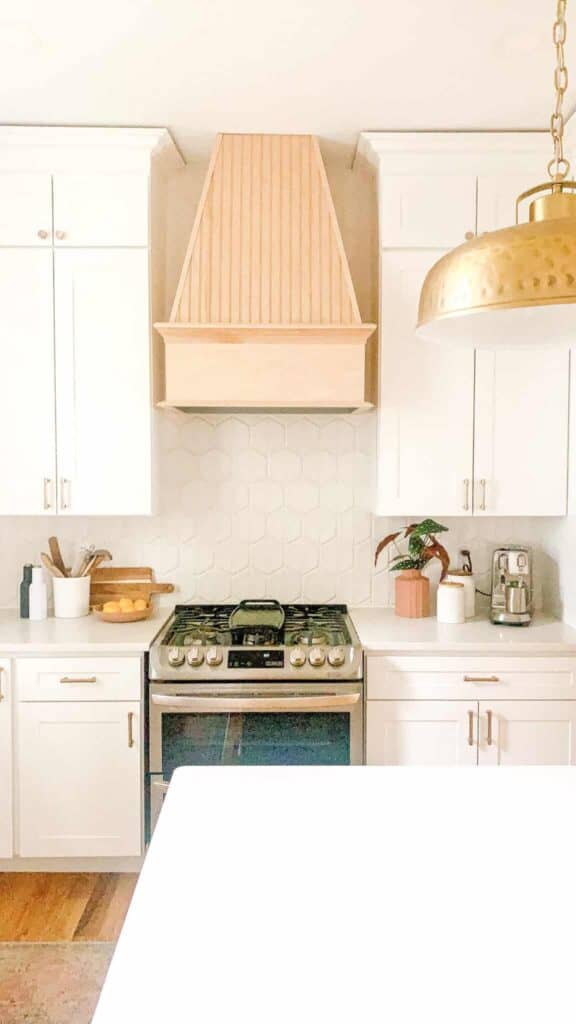 Stove top and range with brass kitchen pendant light hanging over kitchen island.