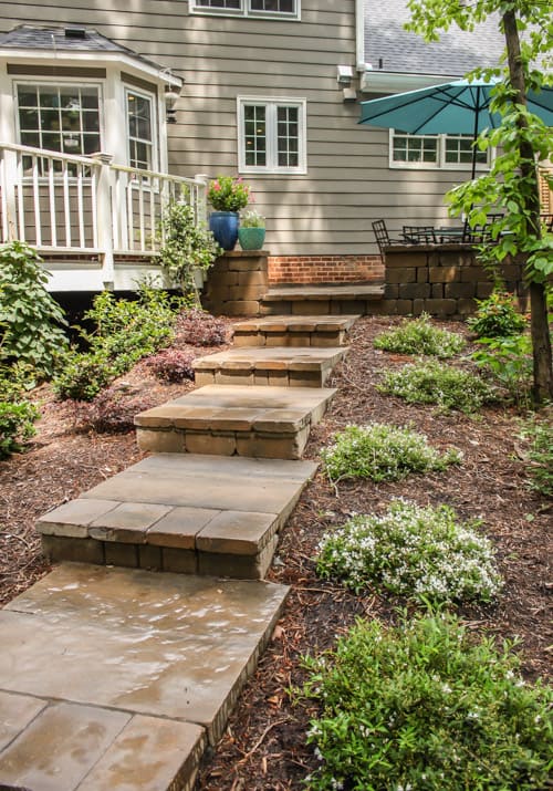Stamped concrete backyard patio steps leads to a wooden oasis.
