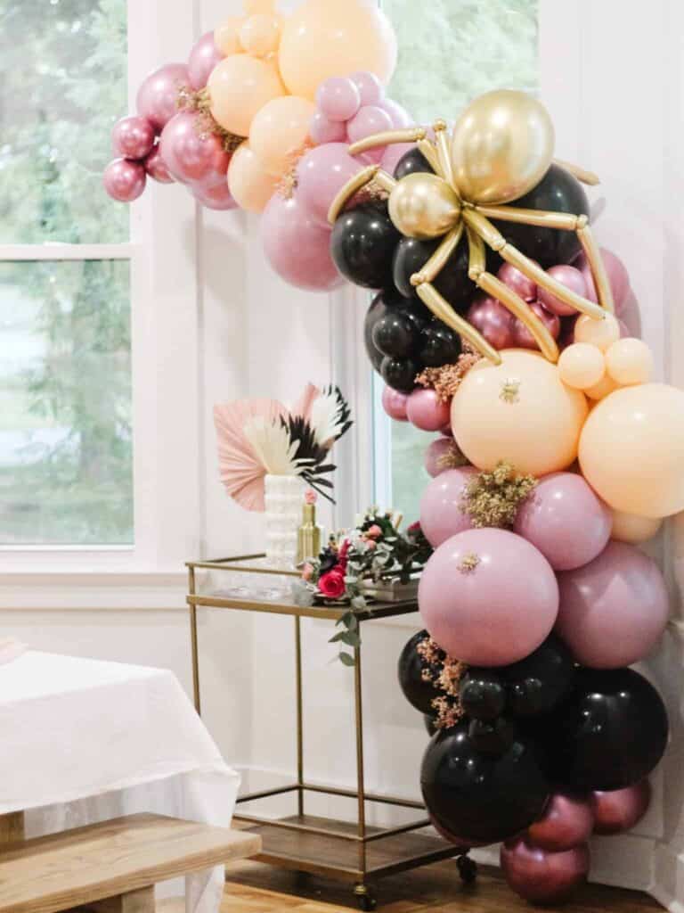 DIY Halloween decorations balloon garland in black, purple, gold, and peach with spiders.
