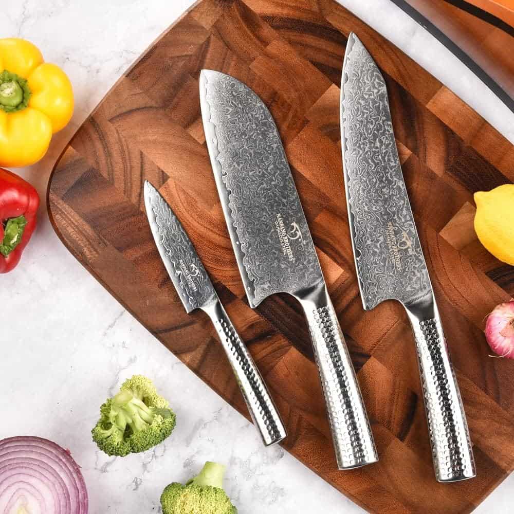 3 piece Damascus kitchen knife set on wooden cutting board with peppers