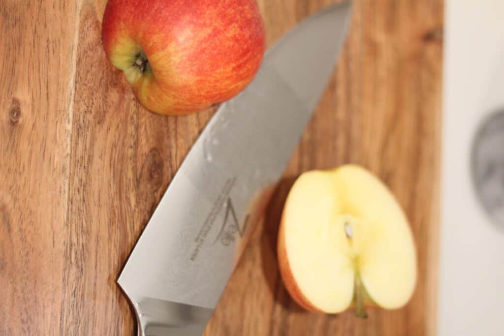 The best Damascus kitchen knife set with wooden cutting board, apple cut in half