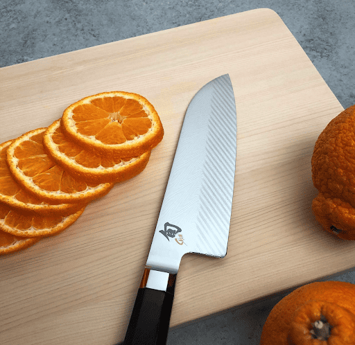 Shun Dual Core 7” Damascus knife next to orange