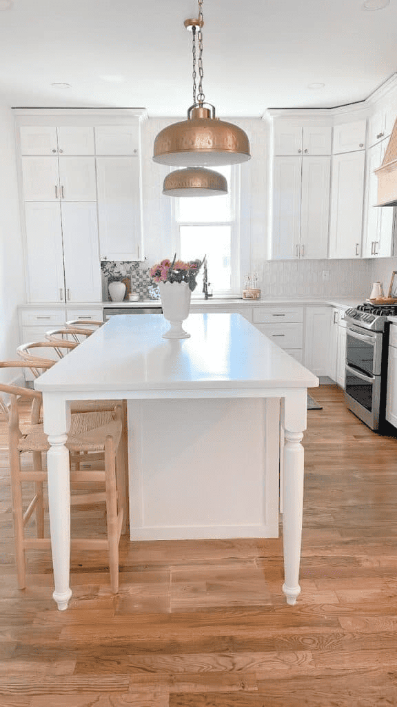 White kitchen island with brass lighting