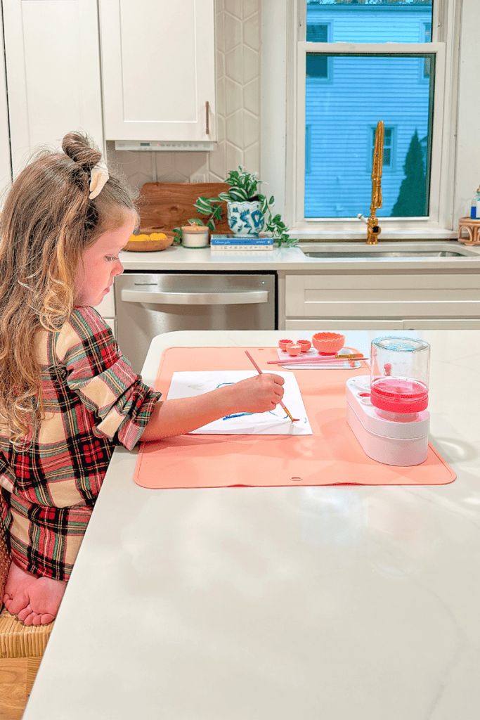 Toddler girl painting at kitchen counter