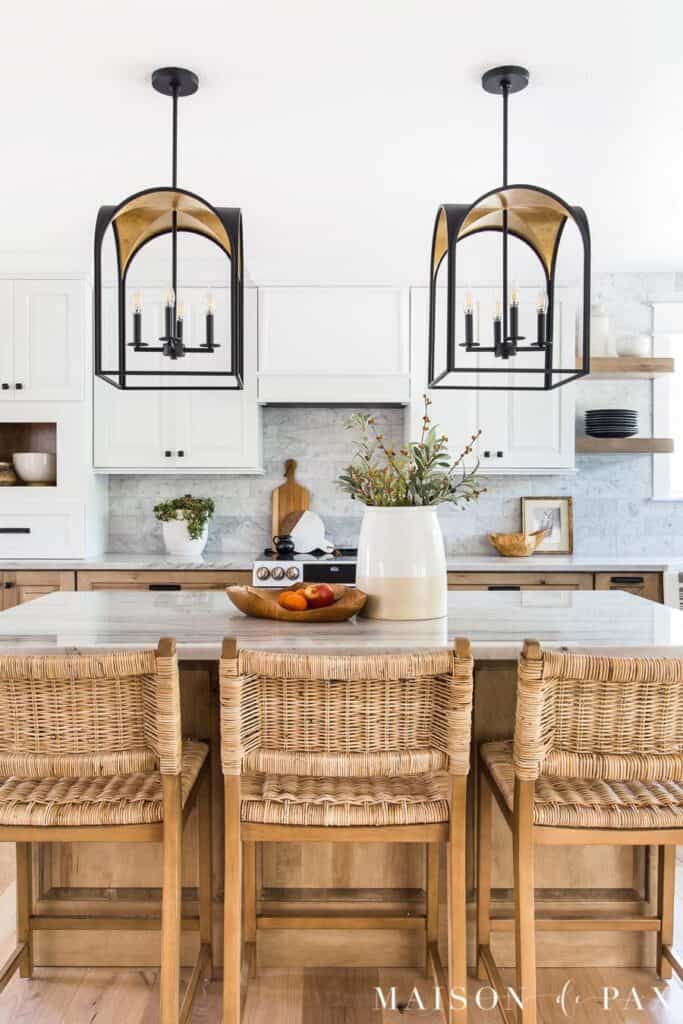 White kitchen cabinets and wicker stools