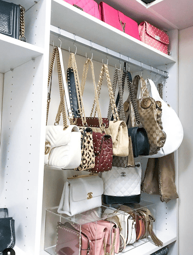 Purses hanging in a closet on s hooks and purse dividers.