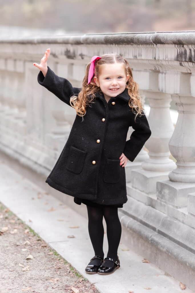 Little girl in black peacoat and pink ribbon