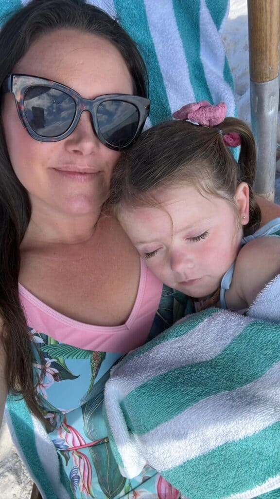 Mom and little girl sleeping at beach