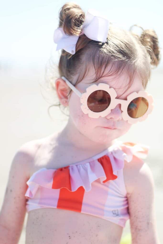little girl at beach with sunglasses on