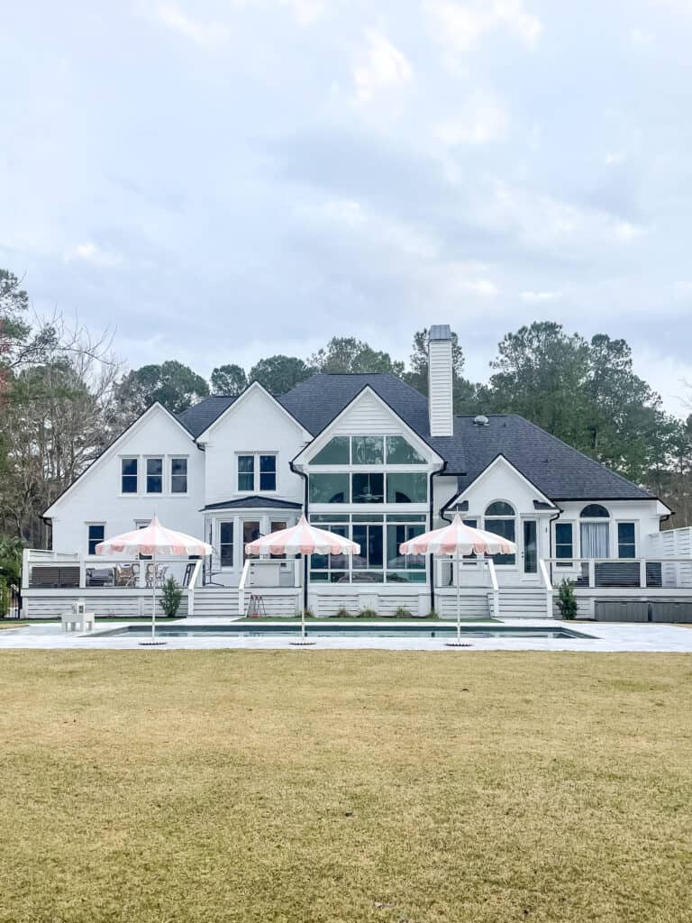 white southern house with white and pink umbrellas at pool